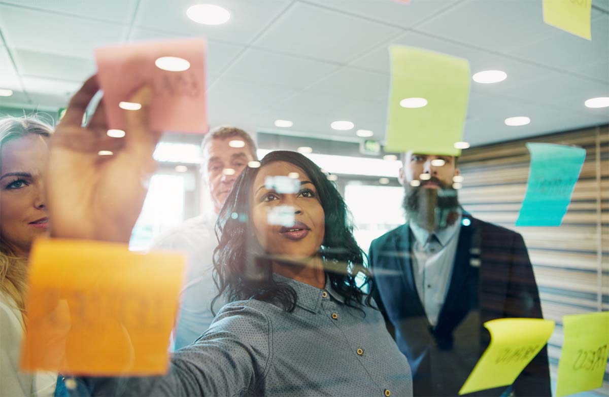 Group of People Writing Down Action Items On Post-It Notes