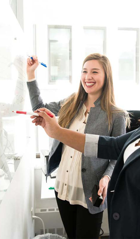 Two Women Standing in Front of Whiteboard Discussing Strategy