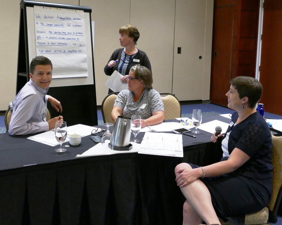 Four Adults Sitting at Table Discussing Action Plan